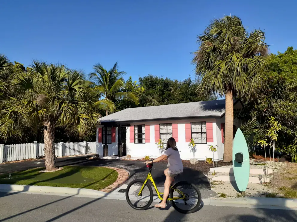 Bike riding past an old house with salmon pink shutters on Love Street. 