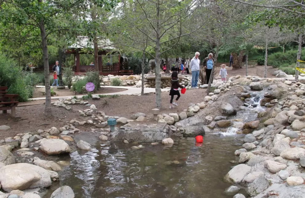 Rock-lined stream outside. See the pagoda and water wheel in the distance.