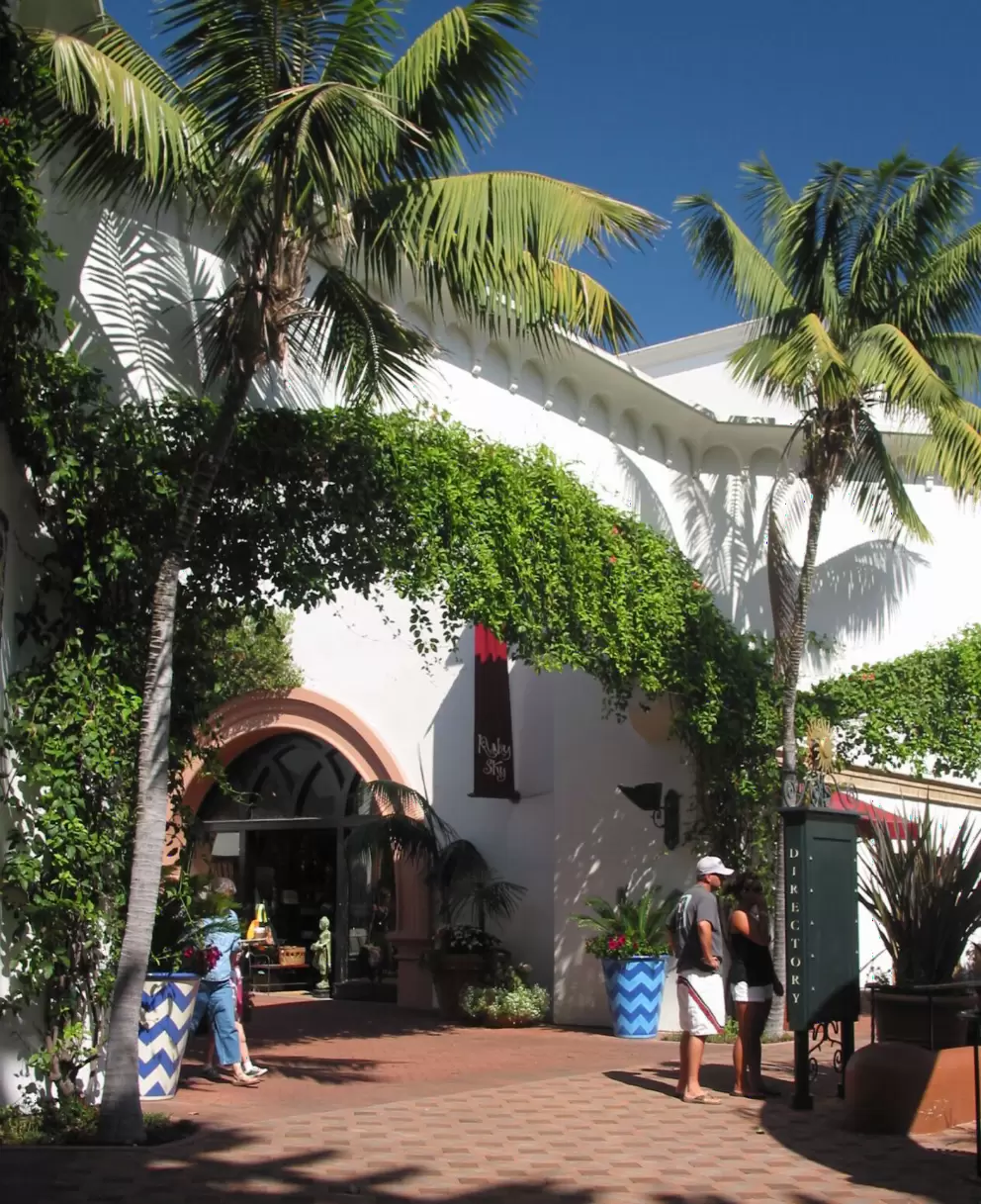The mall area, with shops, flowers, statues, and palms.