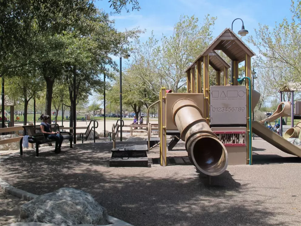 One of many play structures in the center of the park. Shady bench for parents.