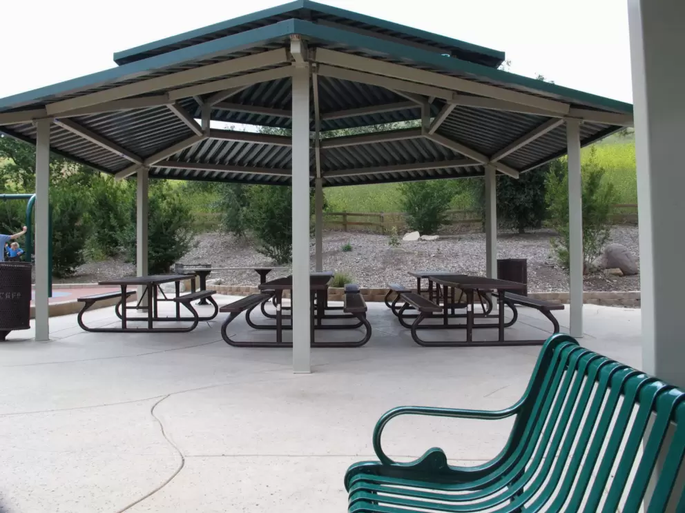 Shaded picnic tables beside the playground.