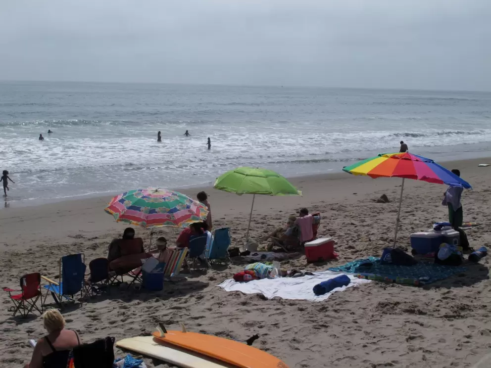 Families enjoy the beach and the cold water.
