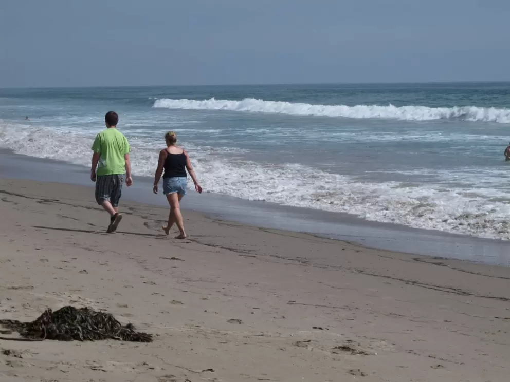 A couple walks on the beach.