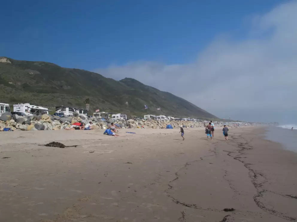 Beach, RVs, and mountains beyond.