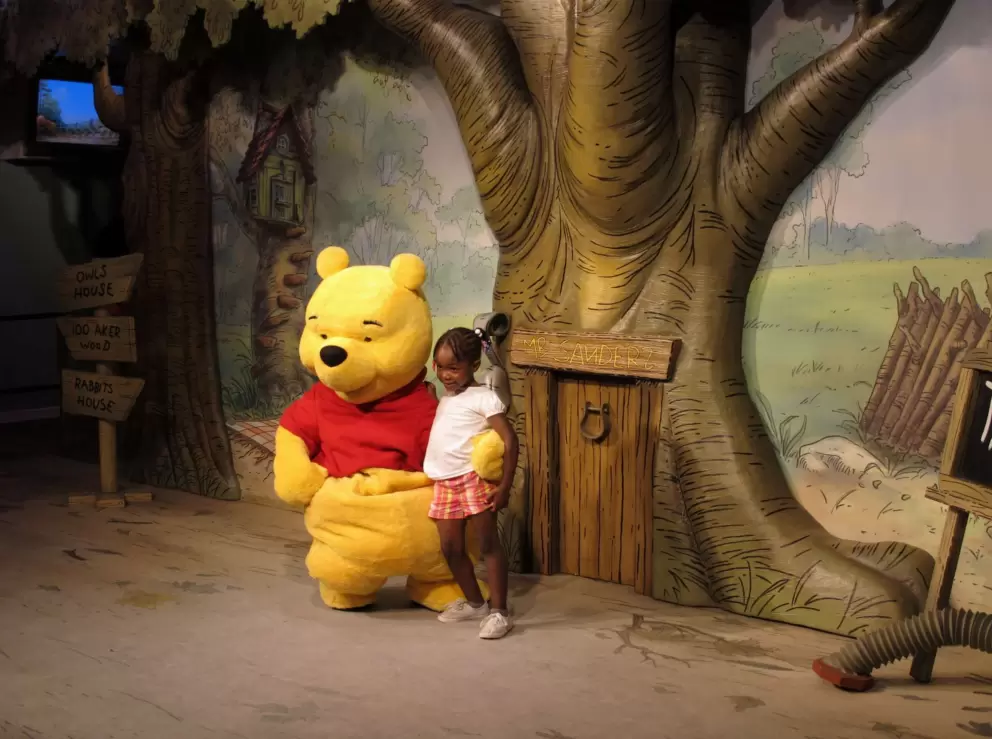 A little girl greets Winnie the Pooh.