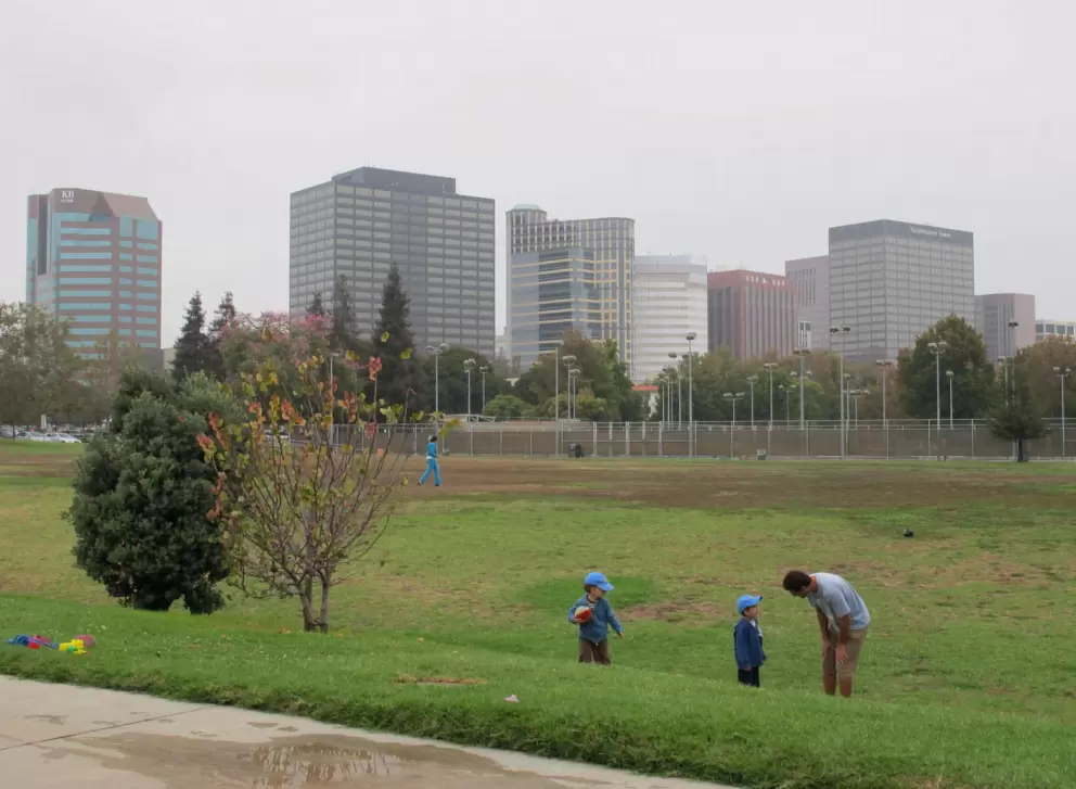 Playing ball on the field by the playground. 