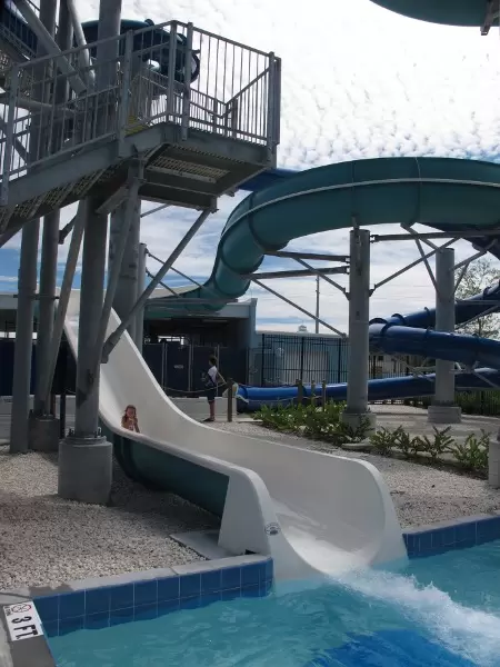A girl slides down the large, open slide.