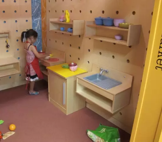 A girl plays quietly in the kitchen area.