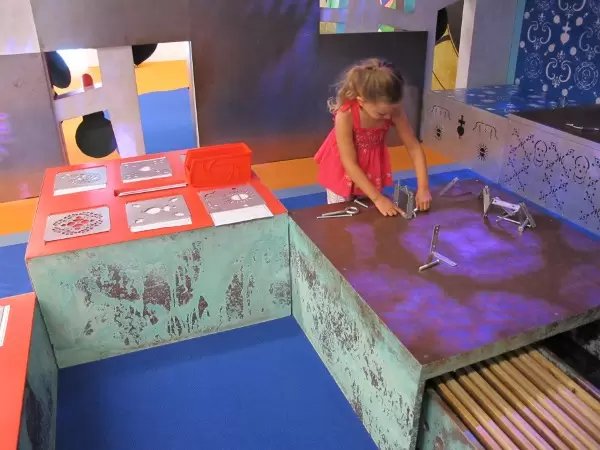 Playing with metal brackets and screws on a magnetic table in the Vodou section of the Culturescapes area.