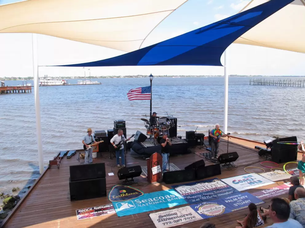 A band plays at the stage surrounded by water on all three sides.