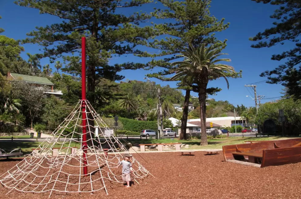 A little girl enjoys the pyramid rope climby at the playground.