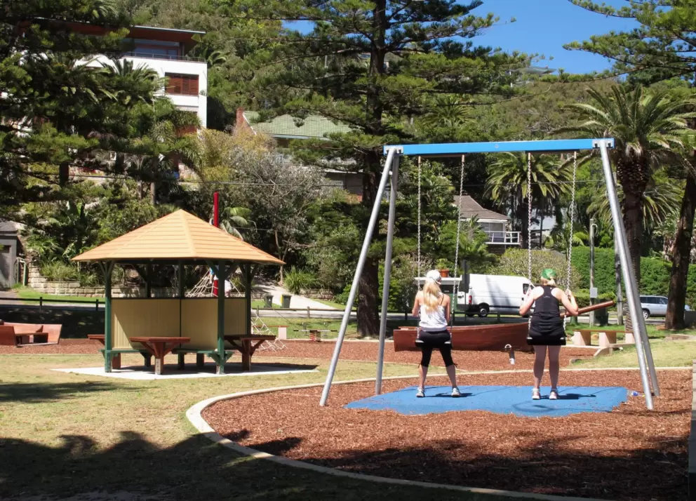 Ladies enjoy a swing while looking up at the Palm Beach beachhouses.