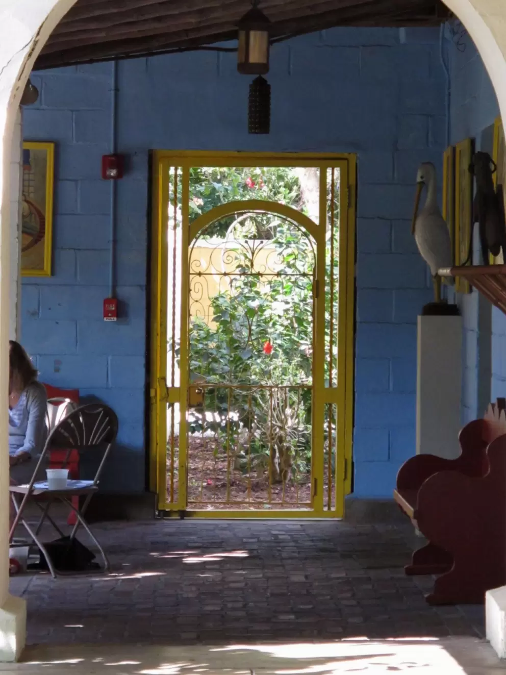 Yellow curlicue door looking out on greenery, plus blue wall.