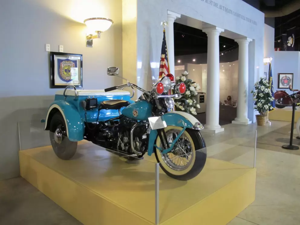 Pale blue motorcycle. Memorial hall in background.