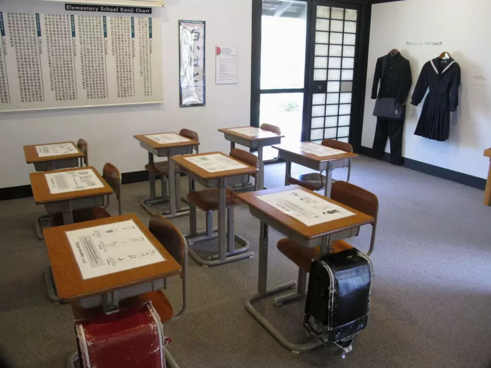 Japanese school classroom, with desks, charts, and uniforms.