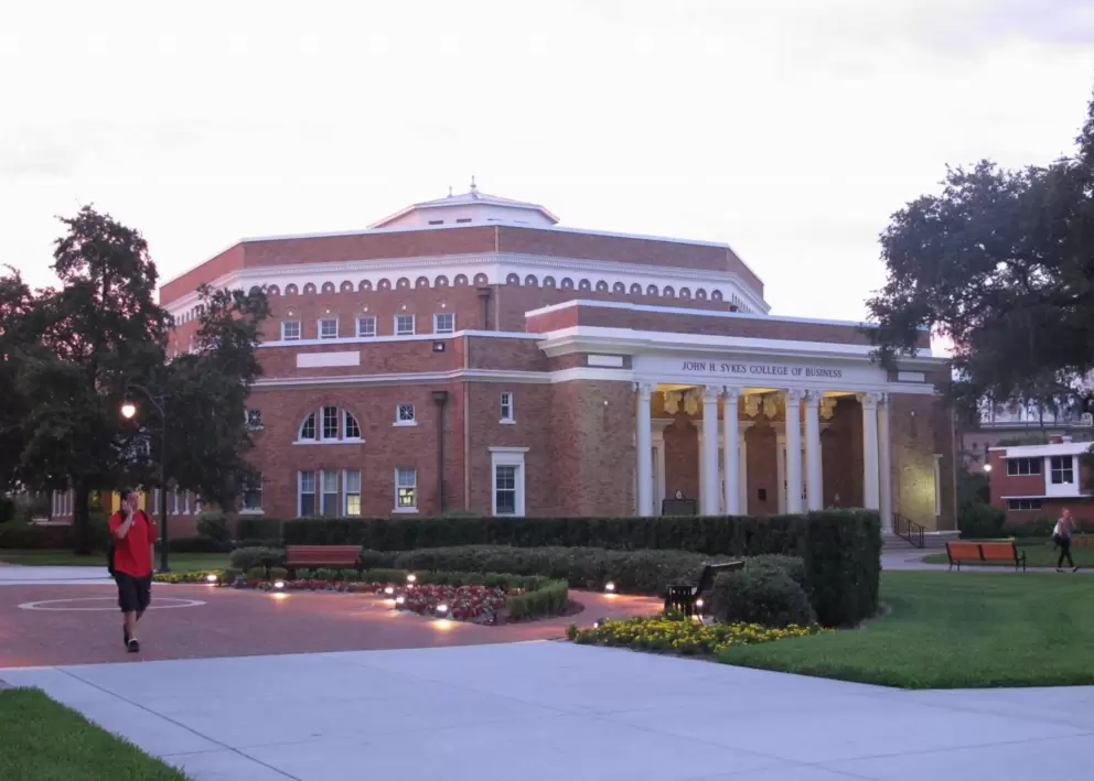A student walks past Sykes College of Business.