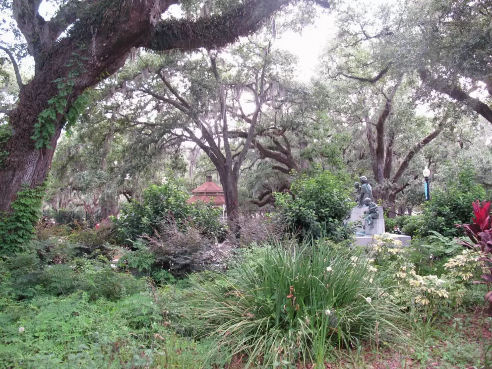 Statue amongst garden plants, flowers, and trees, just outside Carousel Gardens.