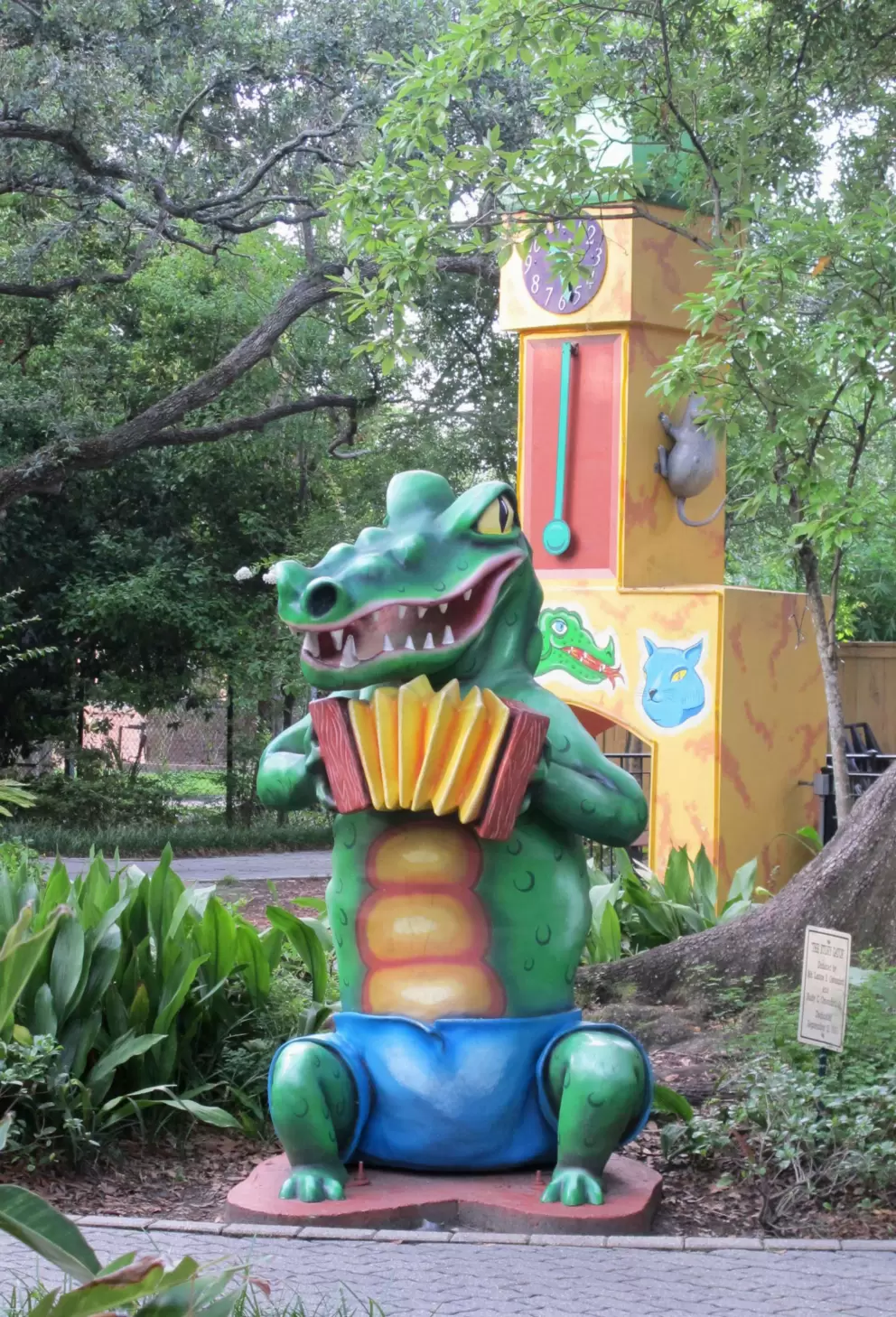 Crocodile playing an accordion, with clock tower behind.