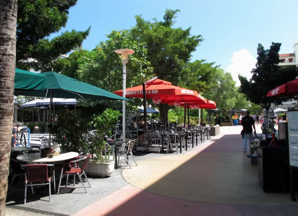 Colorful umbrellas catch the light at the sidewalk cafes.