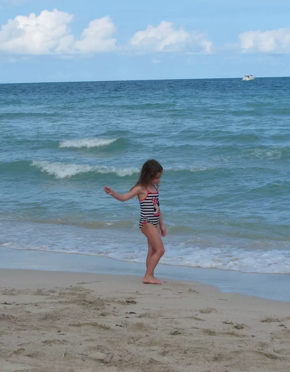A girl walks along the shore.