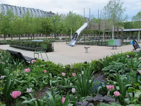 Spacious public garden with toy boats in the pond, rows of groomed chestnut trees, statues, carousel, and playground.