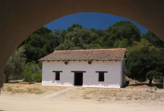 A little building in the back of the mission, as seen through an archway.