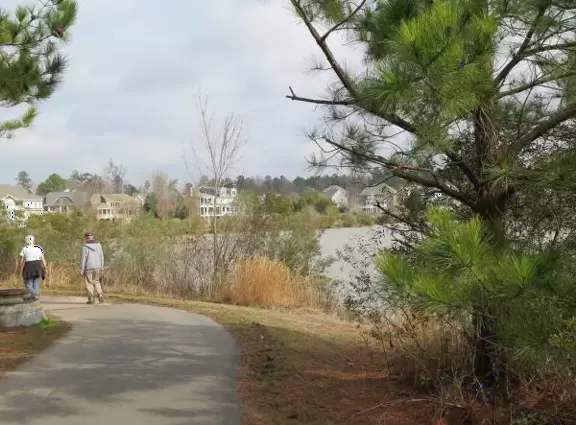 A couple walks the trail beside the lake.