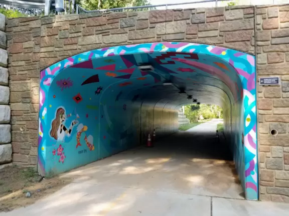Large shady playground with two cool spinners, beach volleyball court, basketball court, and long bike path along a beautiful creek.