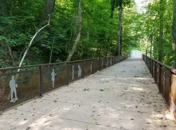 Large shady playground with two cool spinners, beach volleyball court, basketball court, and long bike path along a beautiful creek.