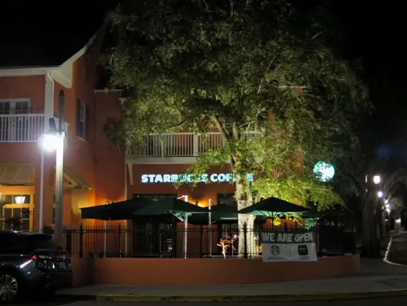 A popular town center with sidewalk cafes leading down to a pretty lake with a walking path.