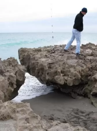 A man walks on a rock while water moves under it.