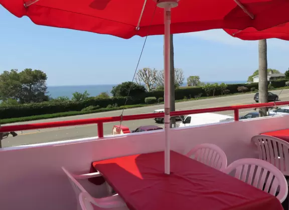 Sit on their rooftop patio under red umbrellas checking out the sea and the hills covered in tropical plants. Check out their 1950s cars and decor!