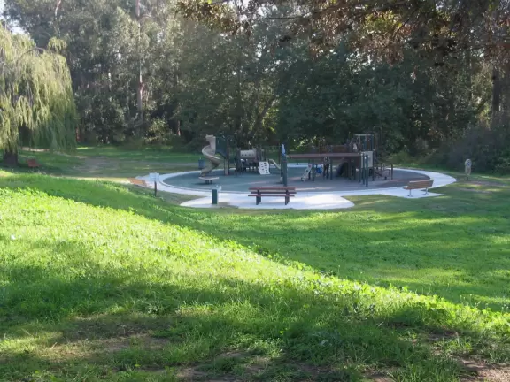 Gorgeous recessed park with a large playground beside meadows and a eucalyptus forest in a suburban neighborhood.