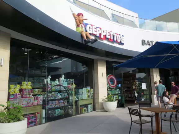 Shopping plaza with a deck offering lots of attractive public space, a trampoline for young kids, a sky deck bar, a dark public market with lights, cafes, stores and coffee shops.
