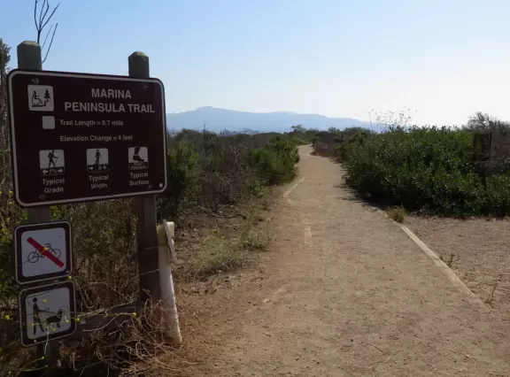 Flat wooden boardwalk loop trail along the estuary- you see divebombing pelicans, Morro Rock, cypress trees on the hills opposite, salt marsh, and mountains in the distance.