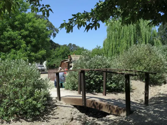 Pristine farm by a hill covered in bright foliage, with oil and vinegar tasting, honey tasting, u-pick, farm store, and adorable kids area with goats, chickens, rabbits, and colorful play areas.