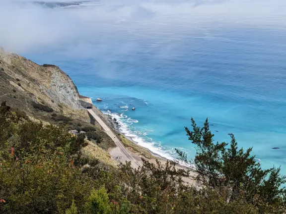 Stunning view from a bench on vertical cliffs above blue-green water.