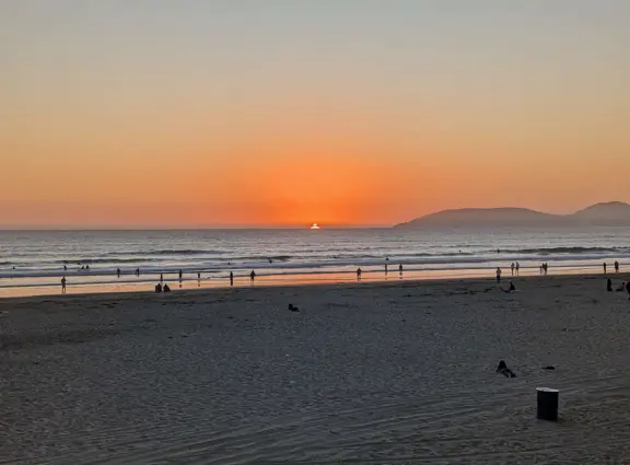 Gorgeous spot with wide pier, surfers carving the waves, whale playground, wide open attractive plaza, Pismo Beach selfie sign, and wooden promenade with views of the hills and sea.