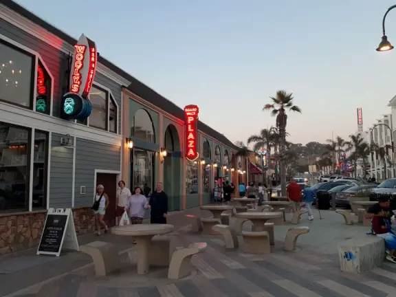 Gorgeous spot with wide pier, surfers carving the waves, whale playground, wide open attractive plaza, Pismo Beach selfie sign, and wooden promenade with views of the hills and sea.