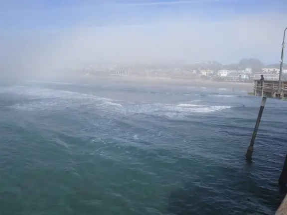 Gorgeous spot with wide pier, surfers carving the waves, whale playground, wide open attractive plaza, Pismo Beach selfie sign, and wooden promenade with views of the hills and sea.