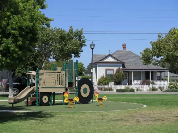 Large lush park with tall tropical trees, attractive bandstand, cute toddler playground, historic house and schoolhouse, swinging bridge to the main street, and neighborhood with cottages.