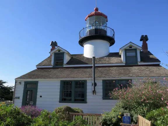 A beautiful, well-cared-for lighthouse with idyllic views of the golf course, dunes, and sea, and a garden with bright flowers.