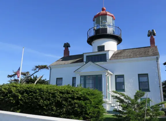 A beautiful, well-cared-for lighthouse with idyllic views of the golf course, dunes, and sea, and a garden with bright flowers.