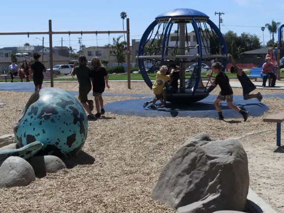 Imaginative playground with dinosaur eggs, huge green lawn, high hills in the distance, and path along the cliffs with views of the ocean and bird rocks!