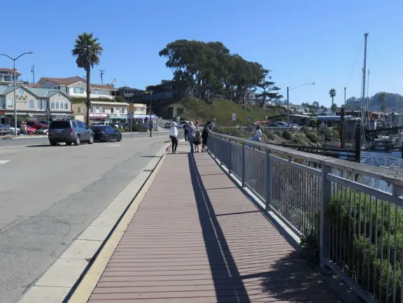 Mother and baby sea otters in a sheltered area near a T-shaped pier. So sweet!