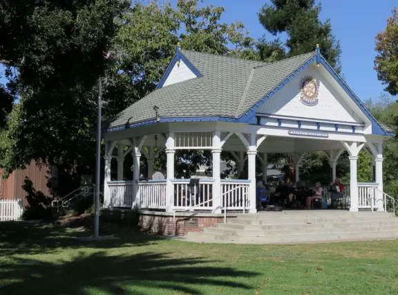 Large lush park with tall tropical trees, attractive bandstand, cute toddler playground, historic house and schoolhouse, swinging bridge to the main street, and neighborhood with cottages.