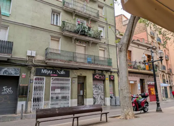 Ironwork balconies, lamppost, bench, and graffiti on Rambla del Poblenou.