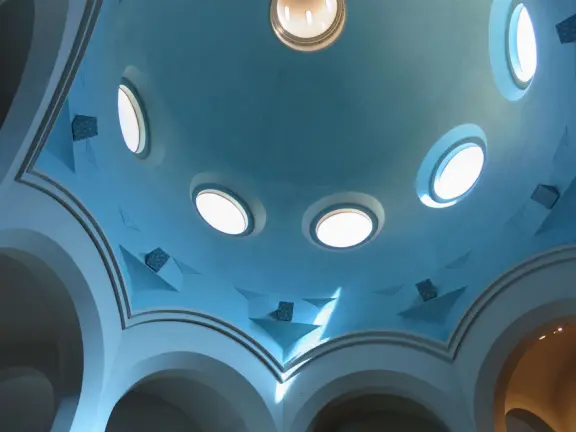 The ceiling rotunda with light shining in circular windows. 
