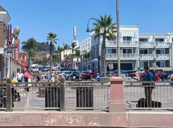 Gorgeous spot with wide pier, surfers carving the waves, whale playground, wide open attractive plaza, Pismo Beach selfie sign, and wooden promenade with views of the hills and sea.