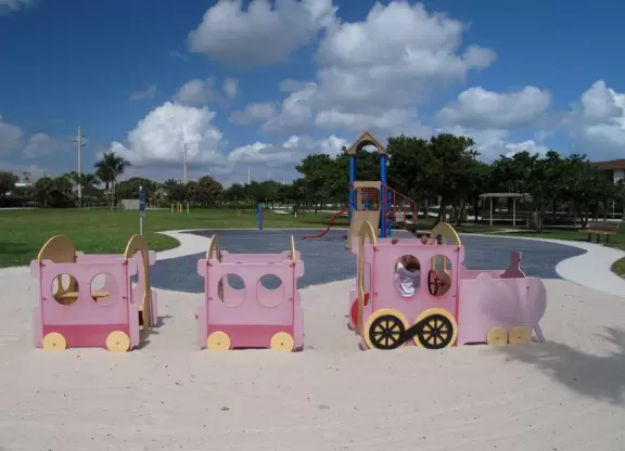 Wide-open park across the street from the beach with playground with pretend train, picnic pavilions, and sand volleyball courts.